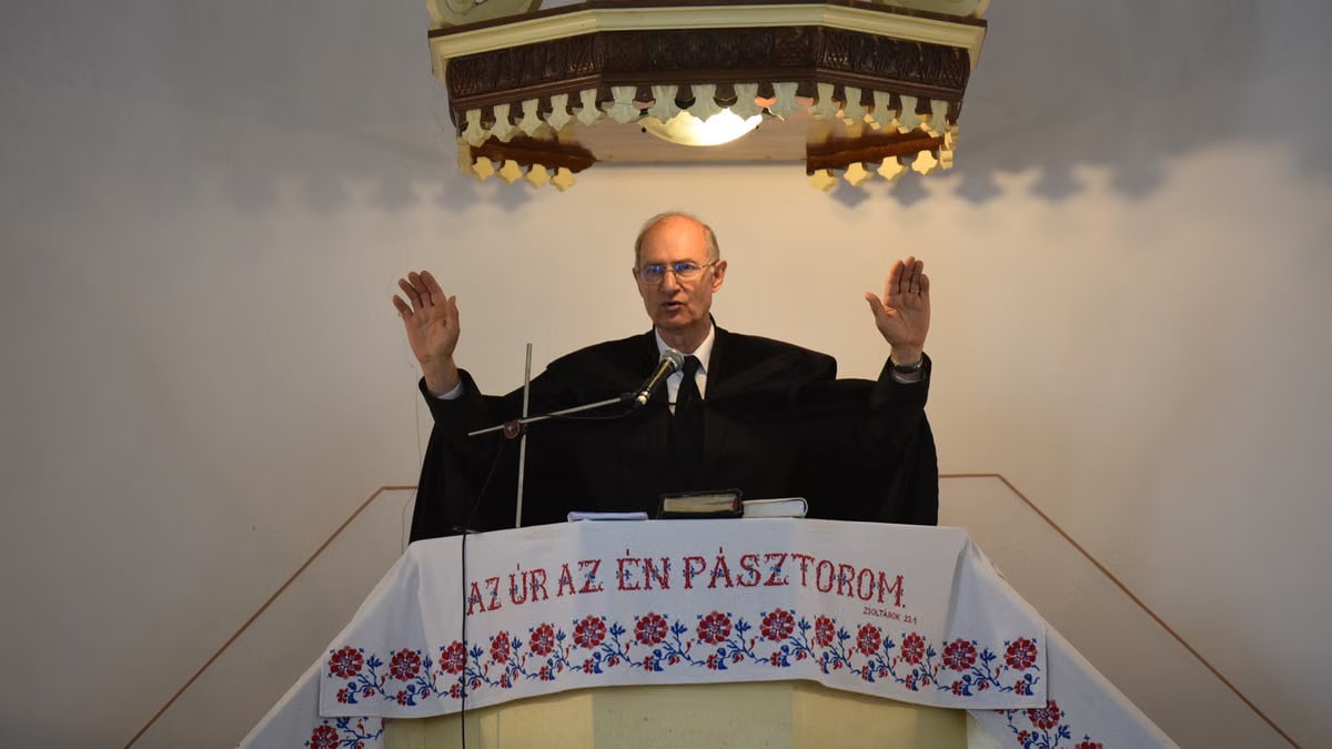 A pastor delivers a sermon inside a church in Vásárosnamény, offering blessings from the pulpit.