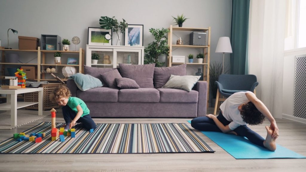a woman and a child playing on a rug in a living room