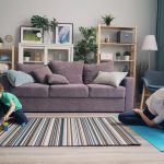 a woman and a child playing on a rug in a living room